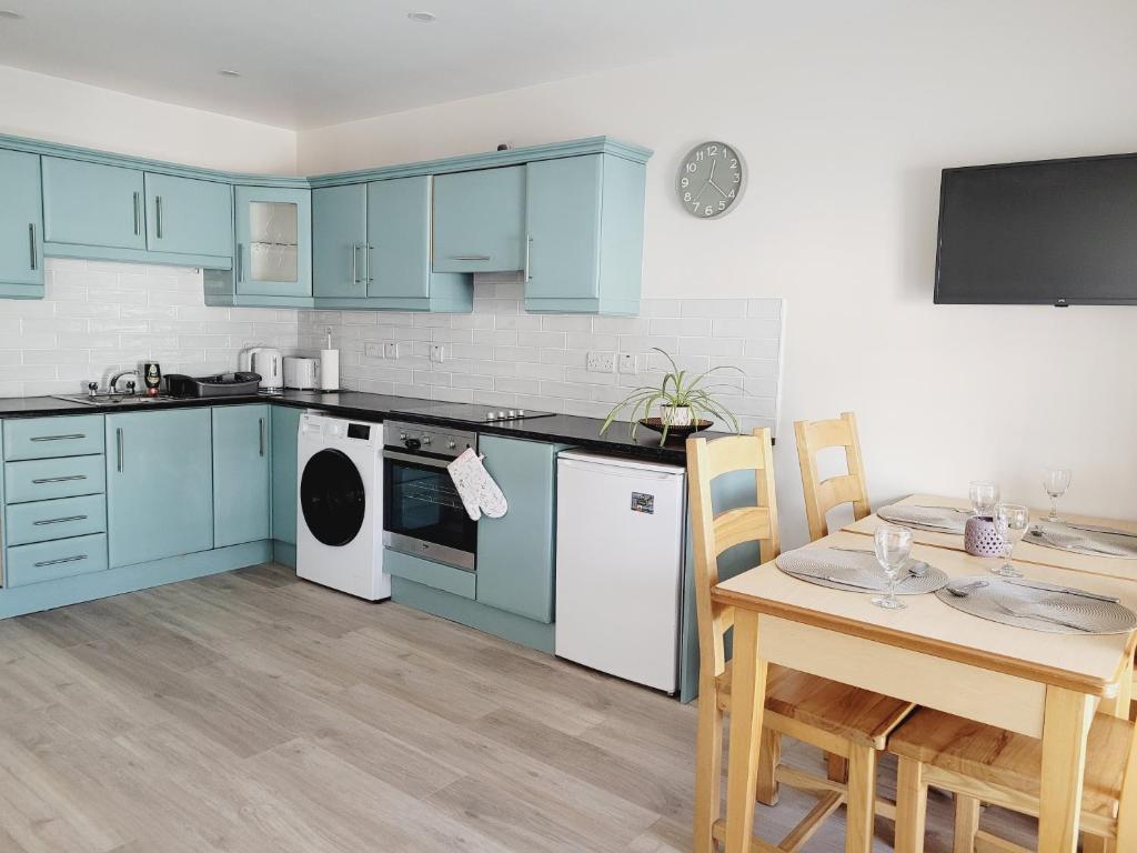 a kitchen with blue cabinets and a table and a dining room at Modern town centre apartment in Tobercurry
