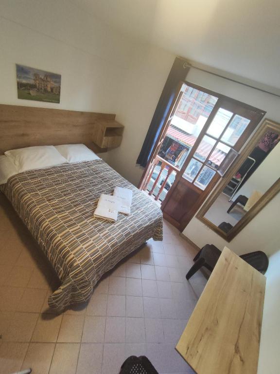a bedroom with a bed and a table and a window at La Pascana Hospedaje in Cajamarca