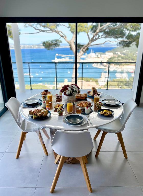 une table avec de la nourriture dessus avec vue sur l'océan dans l'établissement Le Cap Marlou vue d'en bas, à Saint-Mandrier-sur-Mer