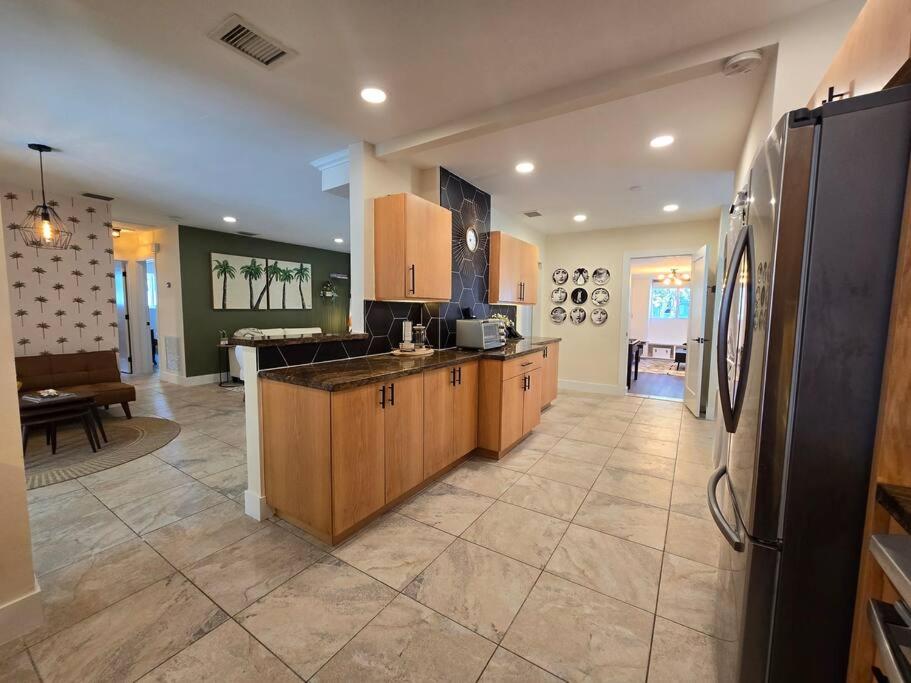 a large kitchen with wooden cabinets and a refrigerator at Palma Haus - Modern Villa with Pool Near the Beach in Hollywood Beach