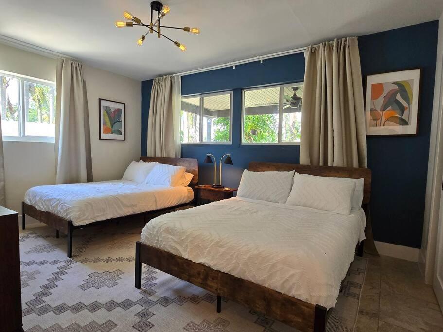 two beds in a bedroom with blue walls and windows at Palma Haus - Modern Villa with Pool Near the Beach in Hollywood Beach