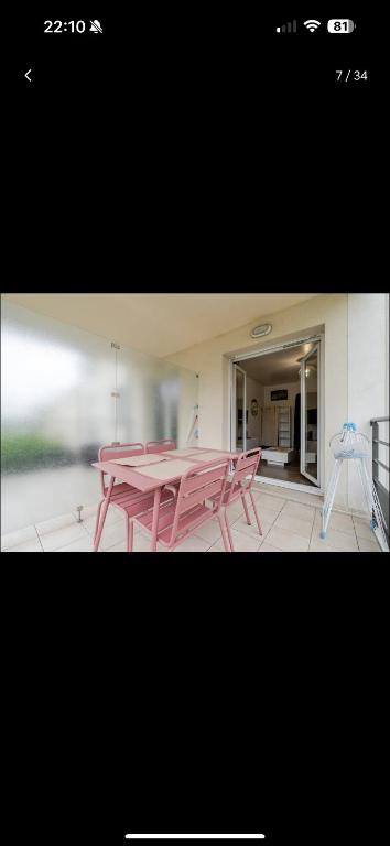 une table et des chaises roses devant un bâtiment dans l'établissement Proche Disney et Paris - Studio terrasse et parking privé, à Montévrain