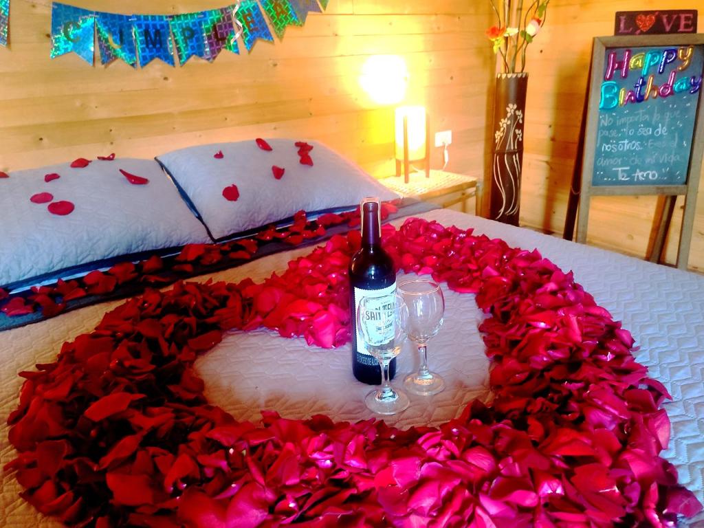 a bed with a heart of roses and a bottle of wine at Montelungo Cabañas Glamping in Chimbe