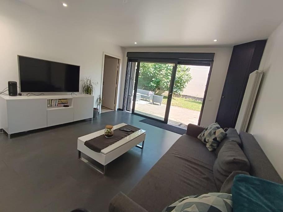 un salon avec un canapé et une télévision à écran plat dans l'établissement Maison - Jacuzzi Jardin Parking proche Paris & CDG, à Drancy