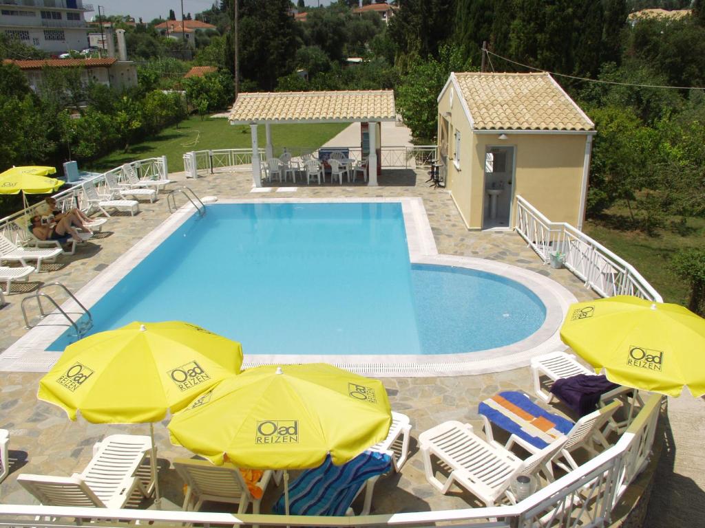 einen Pool mit 2 Sonnenschirmen und Stühlen sowie einem Pool in der Unterkunft Dimitra Apartments G in Gouvia