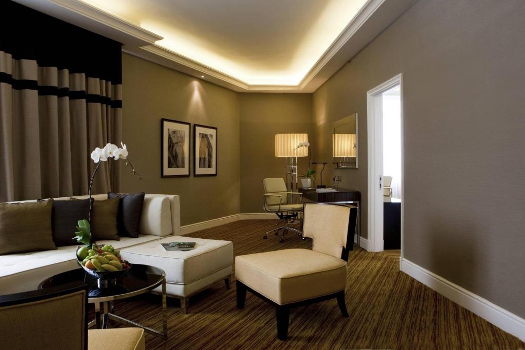 A quiet sitting room with a sofa, two armchairs and a compact desk area.