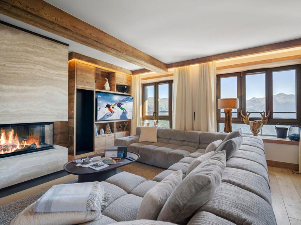 un salon avec un canapé et une cheminée dans l'établissement Luxueux Duplex Courchevel 1850, 3 Chambres, près des Pistes, Parking, Services Inclus - FR-1-564-118, à Courchevel