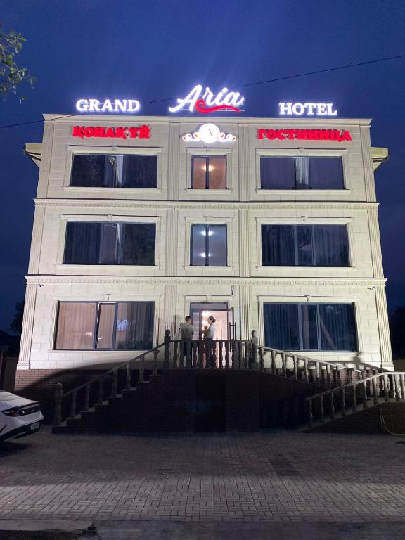 two people standing in front of a hotel at night at Grand ARIA Hotel in Almaty