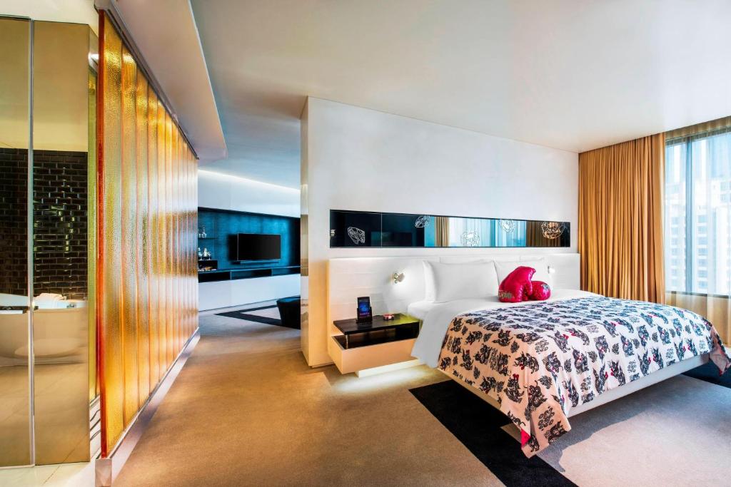 a bedroom with a bed and a tub and a bathroom at W Bangkok Hotel in Bangkok