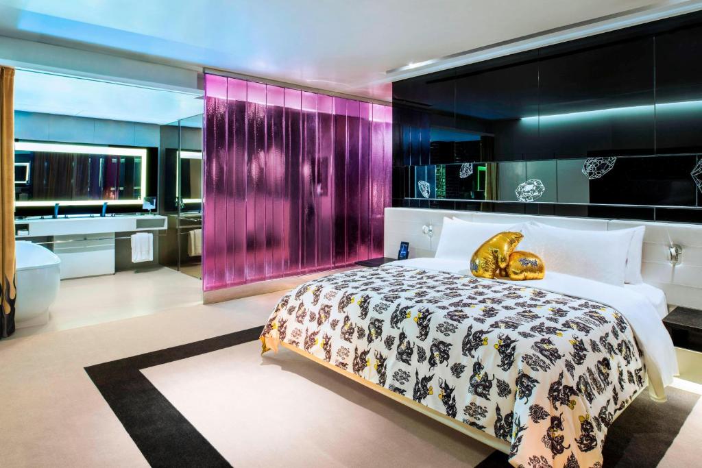 a bedroom with a large bed and a bathroom at W Bangkok Hotel in Bangkok
