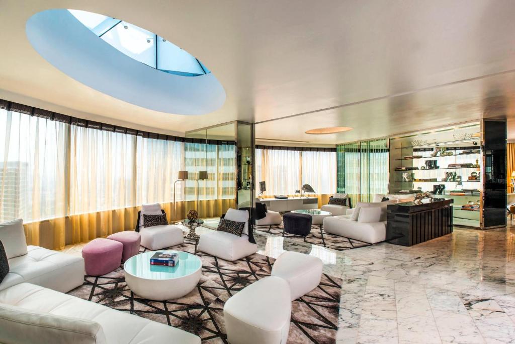 a living room with white furniture and a large window at W Bangkok Hotel in Bangkok
