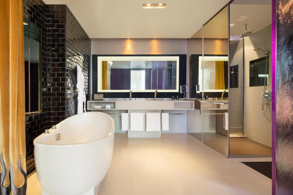 a bathroom with a large white tub and sinks at W Bangkok Hotel in Bangkok
