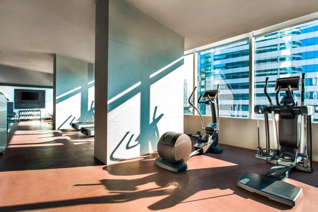 Cardio equipment lines a sunlit gym overlooking neighboring towers.