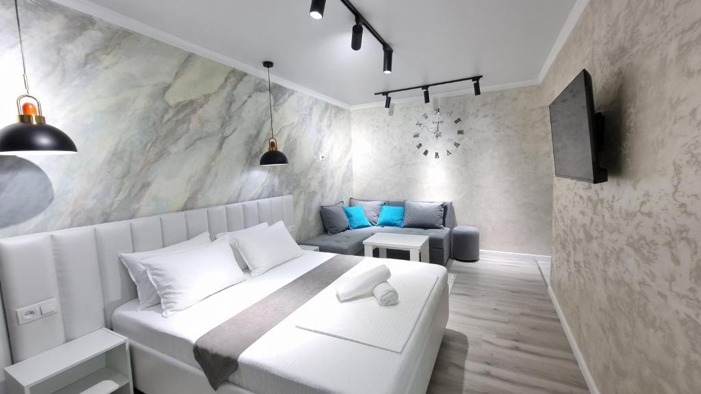 a bedroom with a white bed and a couch at Квартиры на Арбате 2 комнатные in Shymkent