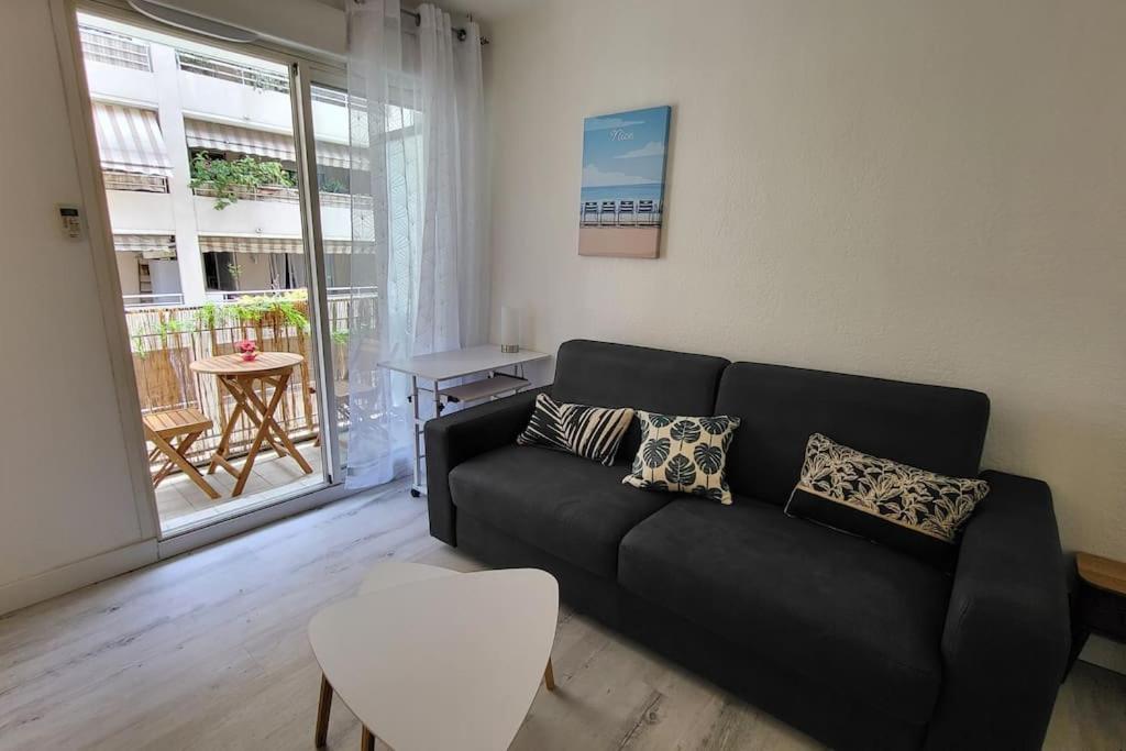 un salon avec un canapé noir et une table dans l'établissement Tournesol de Nice, à Nice