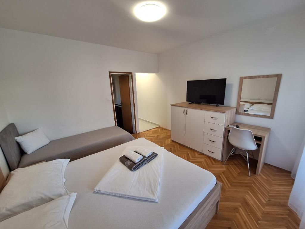 a room with a bed and a tv and a bed and a table at Karmen in Kampor