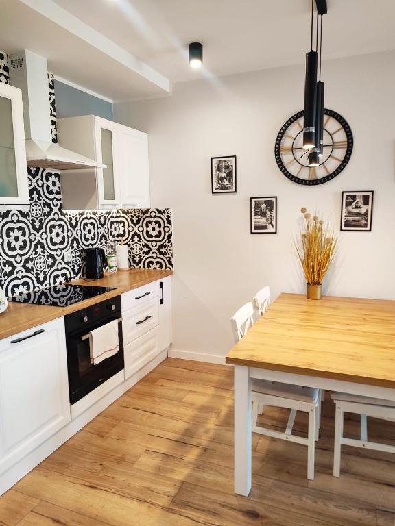 a kitchen with white cabinets and a wooden table at SeaView Apartament in Gdańsk Letnica