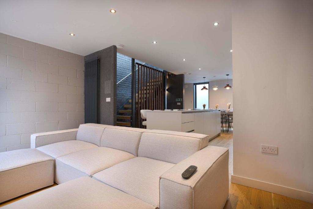 a living room with a white couch and a kitchen at Townhouse East by CasaCity in Manchester