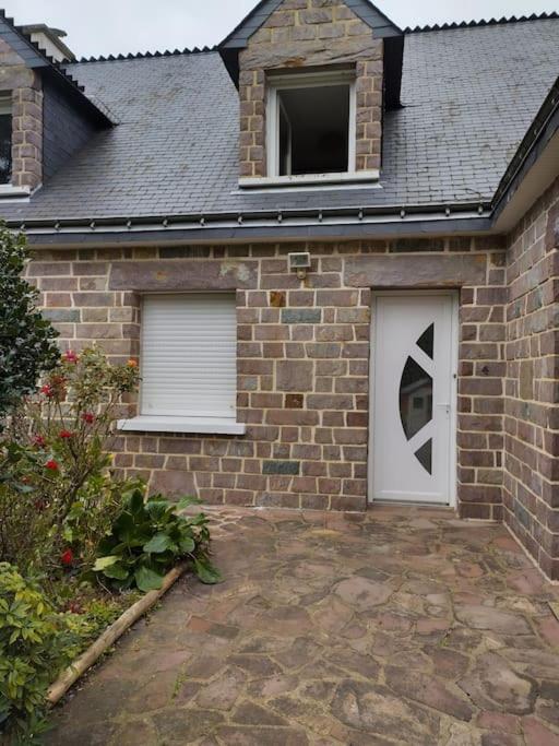 une maison en briques avec une porte blanche et deux fenêtres dans l'établissement M-Houssa, à Saint-Laurent