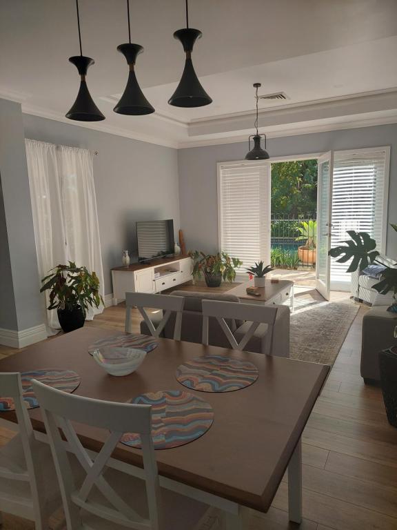 a living room with a table and a dining room at Pool House in Albury