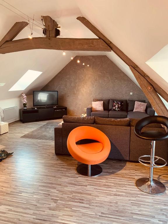 - un salon avec un canapé et une chaise orange dans l'établissement CHAMBRE et JARDIN Village au bord de l eau Cour et Garage privés, à Marcilly-sur-Seine