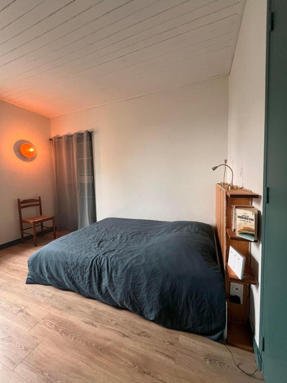 Un dormitorio con una cama con una manta azul. en L’Albizia, en La Tranche-sur-Mer