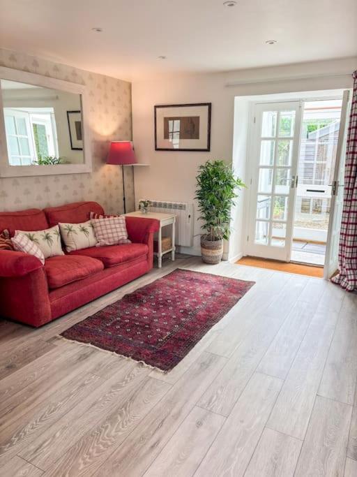 a living room with a red couch and a rug at Cosy flat in Ampney Crucis in Ampney Crucis