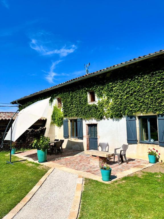 - un bâtiment recouvert de lierre avec une table et des chaises dans l'établissement Le Havre d Adrien, à Illiat