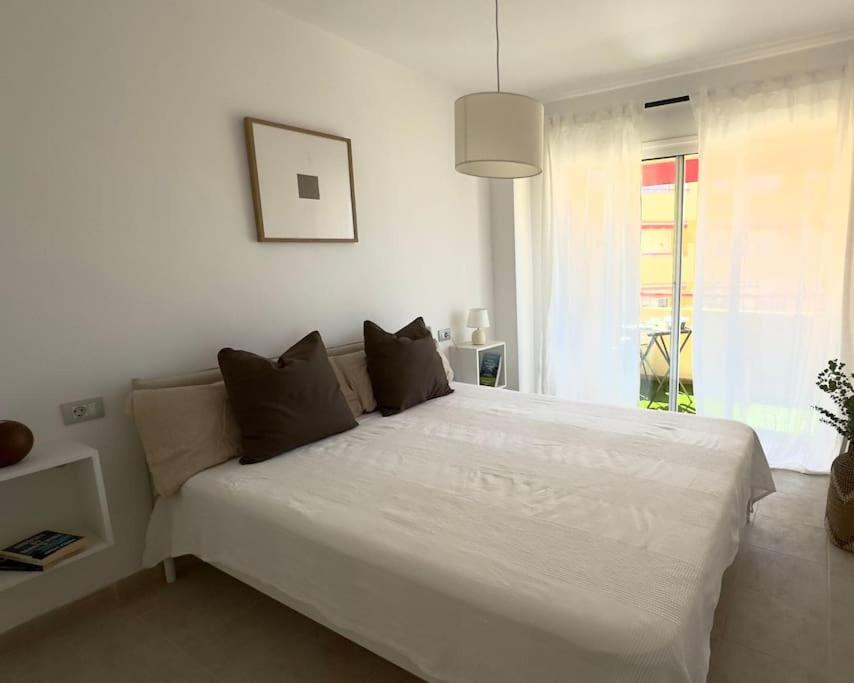 ein großes weißes Bett in einem Zimmer mit Fenster in der Unterkunft Apartamento con Vista al mar y piscina en Puerto Santiago Tenerife in Puerto de Santiago