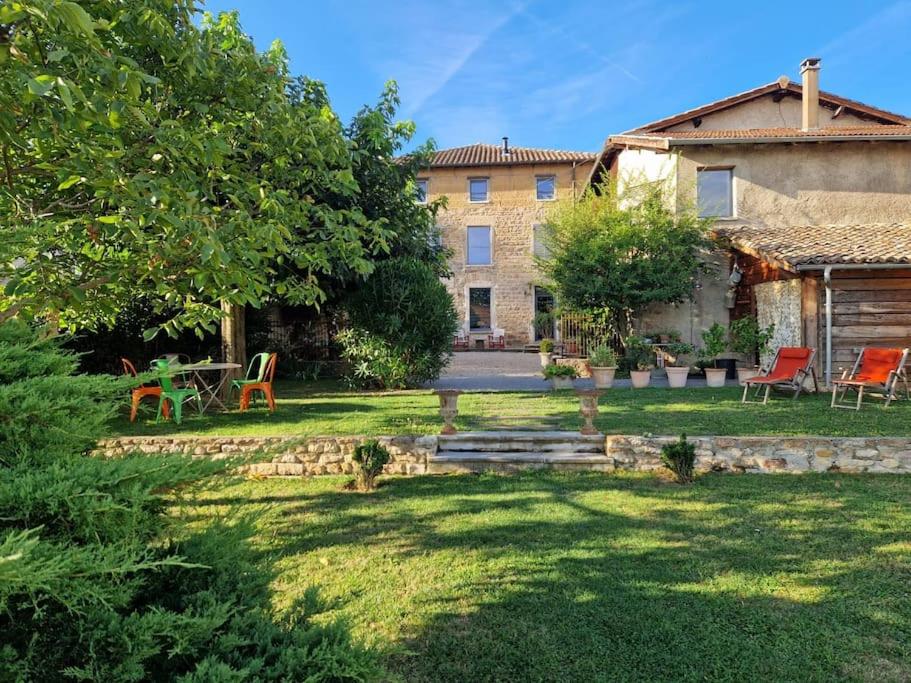 un jardin avec une table et des chaises et un bâtiment dans l'établissement Domaine de famille Aux deux vieux platanes, à Saint-Germain-au-Mont-dʼOr