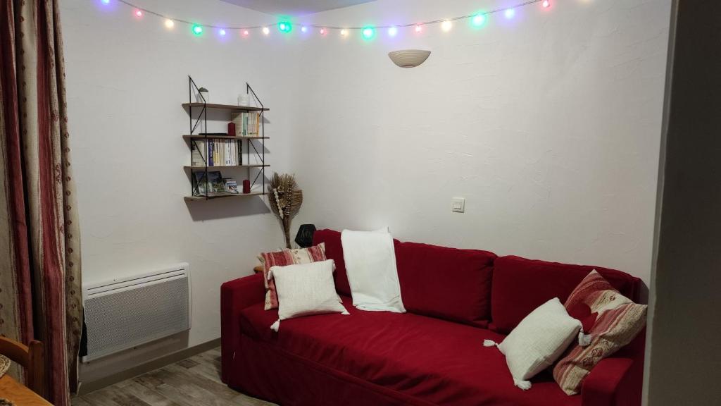 - un canapé rouge dans un salon avec des lumières sur le mur dans l'établissement Oursblanclogis206 Appartement 4 personnes Centre Valmeinier 1800, à Valmeinier