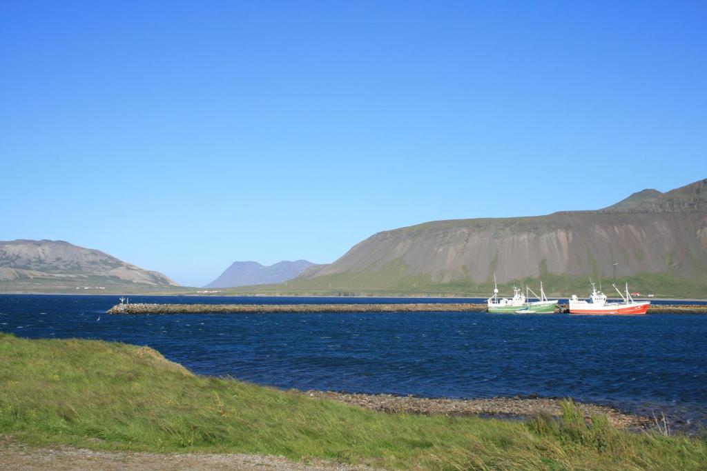 two boats in a body of water with mountains in the background at G4 Apartment in Grundarfjordur