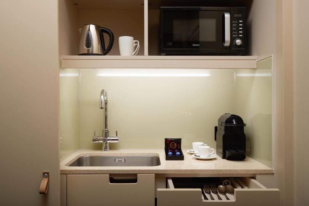 a small kitchen with a sink and a microwave at The Resident Victoria in London