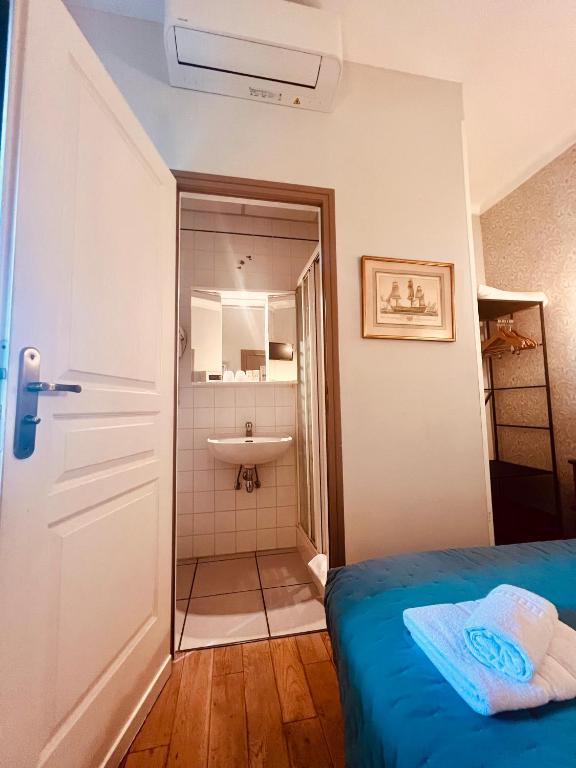 a room with a bed and a bathroom with a sink at Hotel Le Ponteil in Antibes