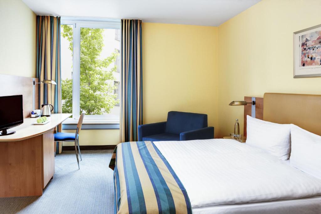 a hotel room with a bed and a desk and a window at IntercityHotel Düsseldorf in Düsseldorf