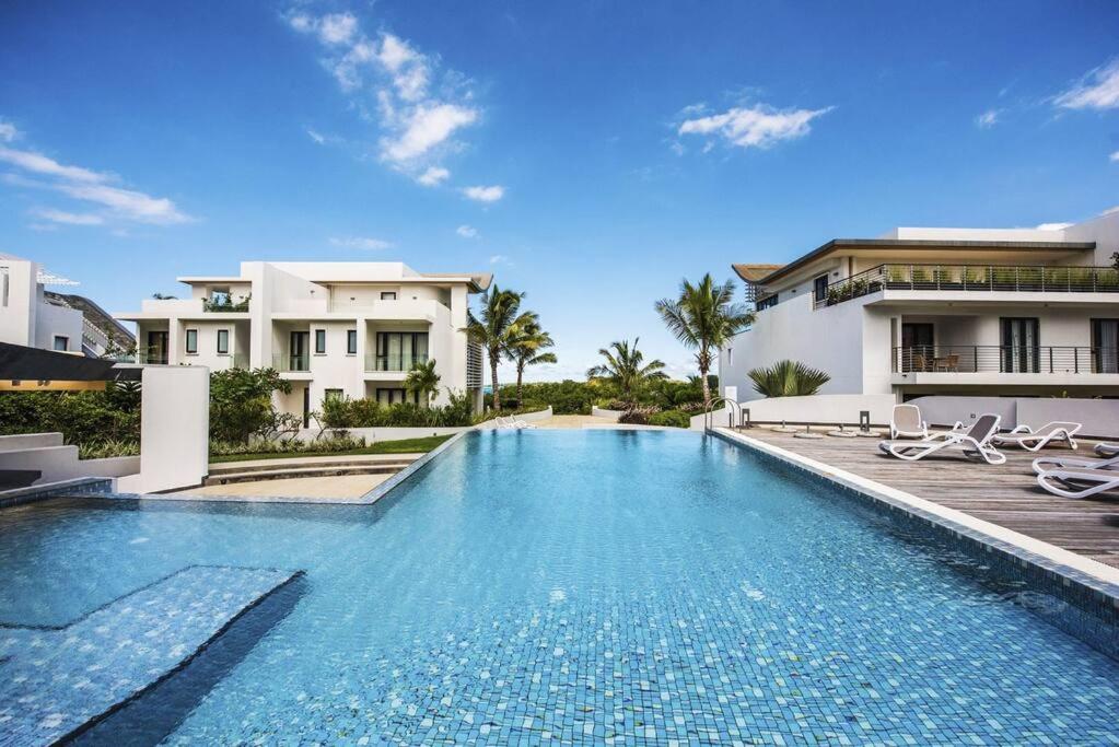a swimming pool in front of a house at Luxury 3 Bedroom Apartment Sea View Azuri Estate in Roches Noires