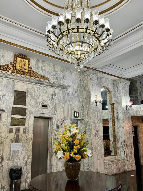 a dining room with a chandelier and a table with flowers at Hotel OK in Rio de Janeiro