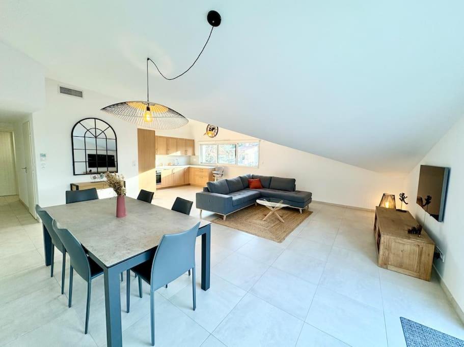 a living room with a table and a couch at Appartement 3 chambres, piscine, 50 m des plages in Les Lecques