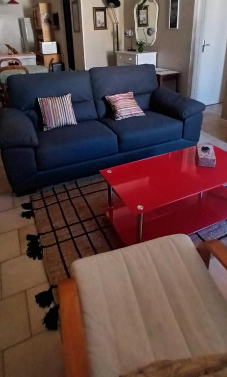 un salon avec un canapé bleu et une table basse rouge dans l'établissement appartement grand confort coeur de ville, à Narbonne