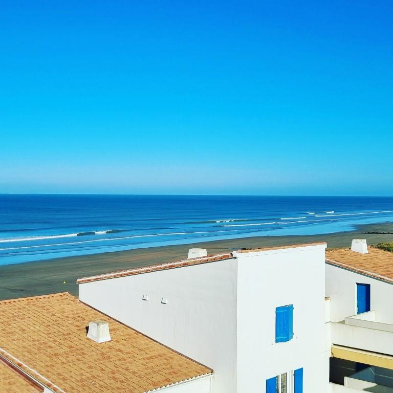 - une vue sur un bâtiment blanc et l'océan dans l'établissement Vue magnifique sur l'océan et les dunes !, à Saint-Hilaire-de-Riez