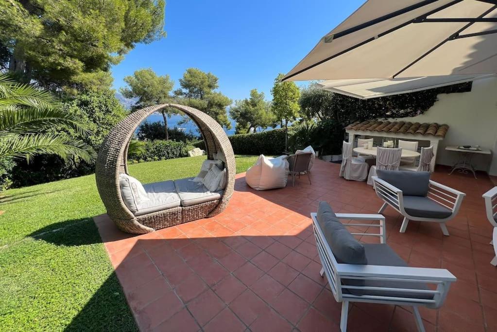 een patio met een rieten stoel en een parasol bij Villa Eden Cap Martin in Roquebrune-Cap-Martin