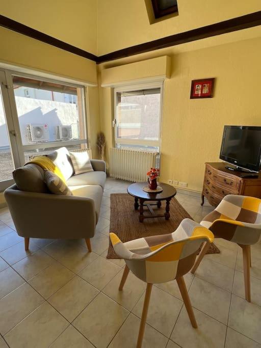 un salon avec un canapé, des chaises et une télévision dans l'établissement Gîte Mamie Berthe, à Sélestat