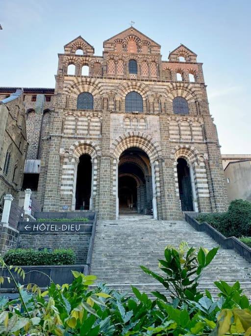 un grand bâtiment en briques avec un panneau devant lui dans l'établissement Le Refuge Cathédrale - Le Puy-en-Velay, au Puy-en-Velay