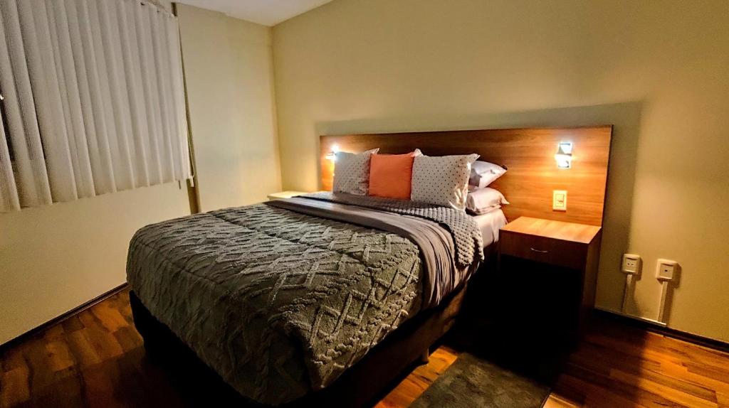 a bedroom with a large bed with a wooden headboard at Departamento céntrico y amoblado La Paz in La Paz
