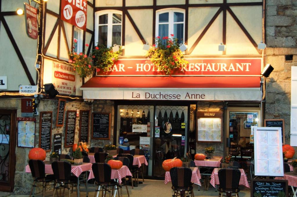 een restaurant met tafels en stoelen voor een gebouw bij Duchesse Anne in Dinan
