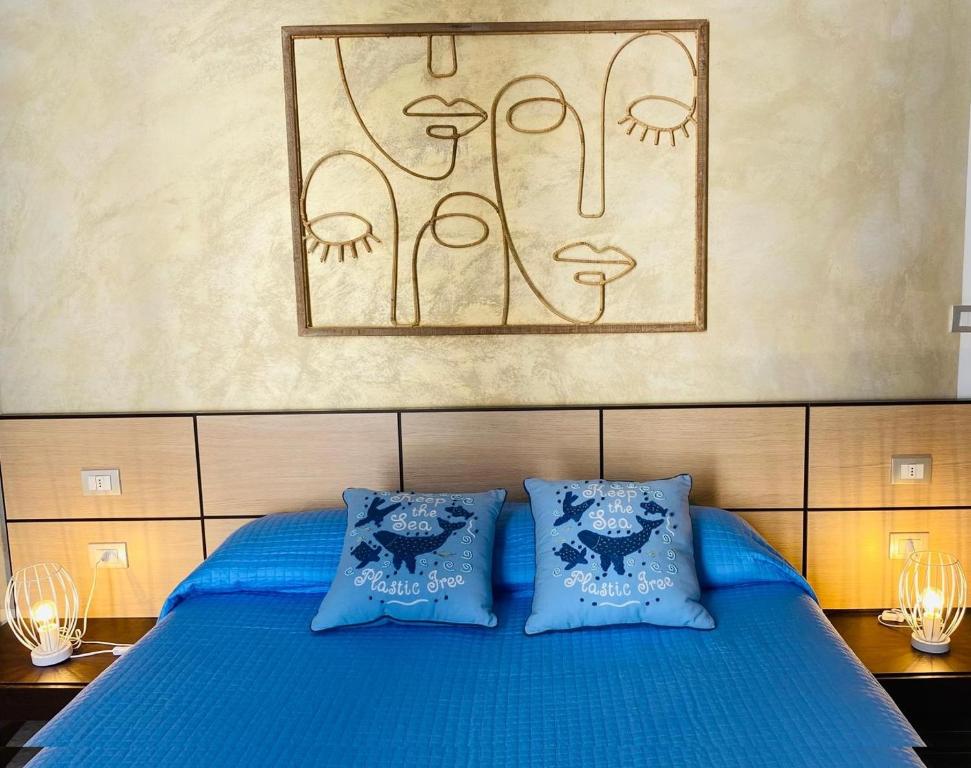 a bed with blue pillows and a painting on the wall at Palmieri Cozy Stay in Monopoli