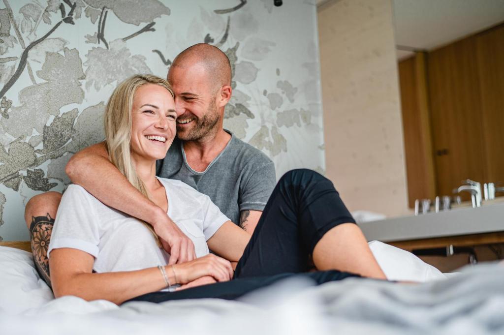 Ein Mann und eine Frau auf einem Bett in der Unterkunft Stock & Stein Lodges in Bad Gleichenberg