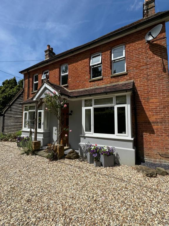 a brick house with a gravel driveway at Beulah Villa in Slinfold