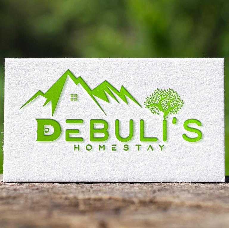 Un cartel para una casa con un árbol y montañas. en Debuli's Home Stay, en Almora