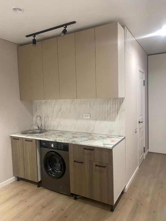 a kitchen with a washing machine in a room at ЖК Алма Сити in Raimbek